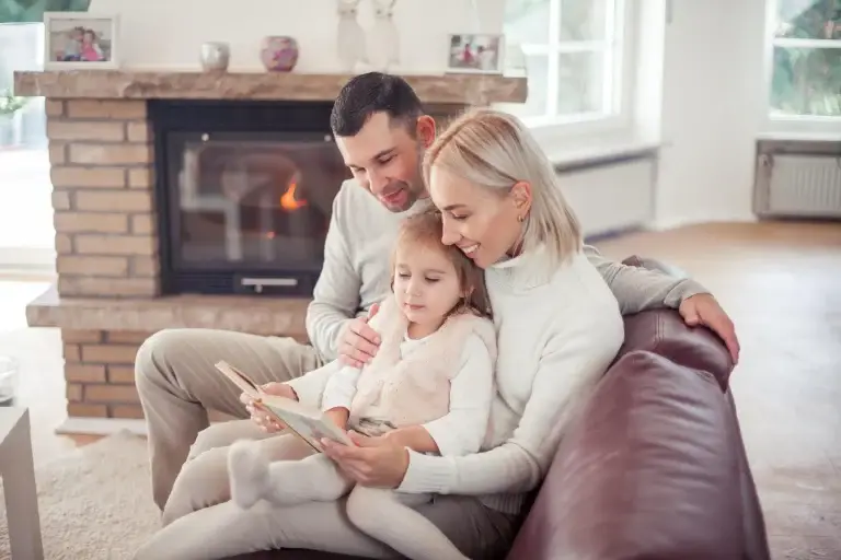 Family reading together on the couch by the fireplace