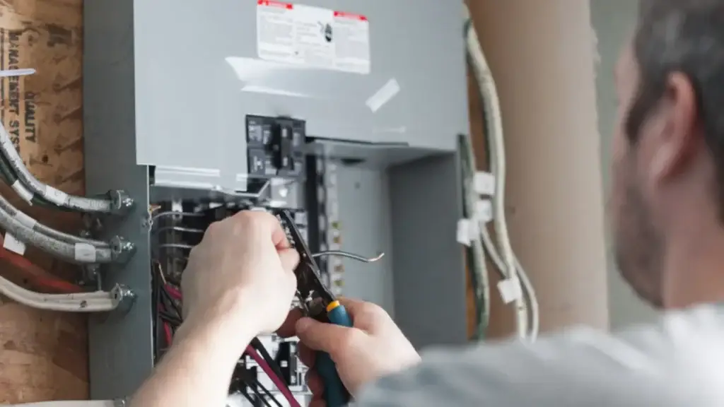 Electrician stripping a wire while connecting circuits in a new breaker panel